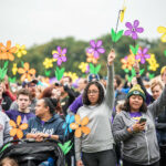 The 2018 Walk to End Alzheimer’s by the Alzheimer’s Association Illinois Chapter. This photograph displays the crowd of people gathered to walk, holding up forget-me-not flowers, which are the symbol of remembrance for those with Alzheimer's.