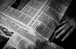 A hand touches a newspaper. Hayden Walker via Unsplash