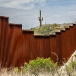 Image of the US border wall in an arid landscape.