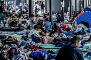 Dozens of migrants lay on the floor, clustered together.