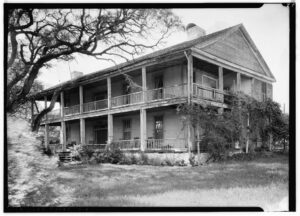 Photo of the Seward Plantation House, in Independence Texas. It is a two story structure, rectangular shape with a large two story front porch running the length of the home
