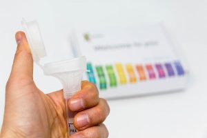 A saliva kit, users introduce their saliva, which is then mailed back to the company for genetic analysis. | Hand holds Saliva Collection Kit Tube from 23andMe with open funnel lid to test health and ancestry with personal genetic in front of blurry background | Courtesy of CCNull