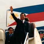 A picture of Ferdinand Marcos waving to a crowd from the steps of his plane.
