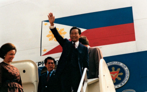 A picture of Ferdinand Marcos waving to a crowd from the steps of his plane.